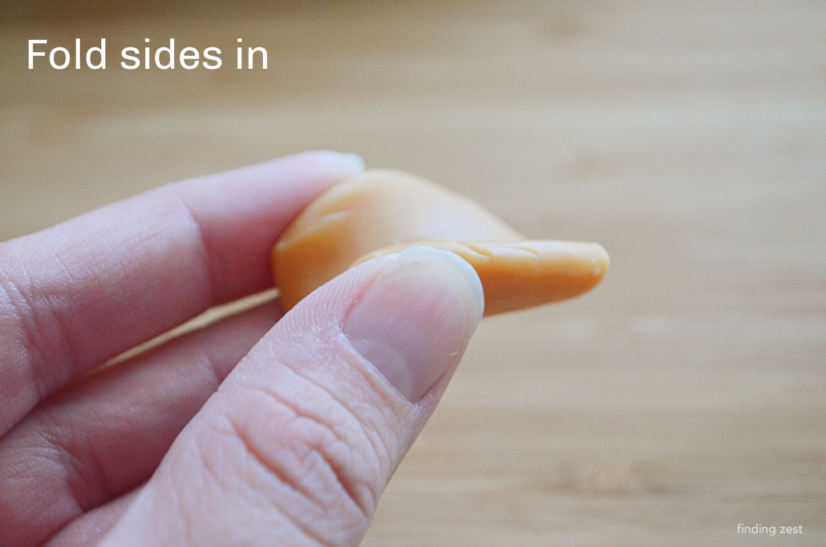 Folding a flattened caramel to make a candy hot dog bun.