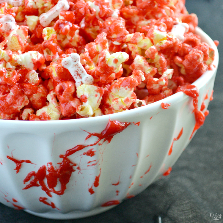 Learn how to make bloody popcorn with bones including directions for adding edible fake blood to your serving dishes! Halloween popcorn has never been so fun and it makes a great snack to serve Halloween party guests!