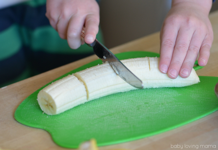 Three year old slicing bananas