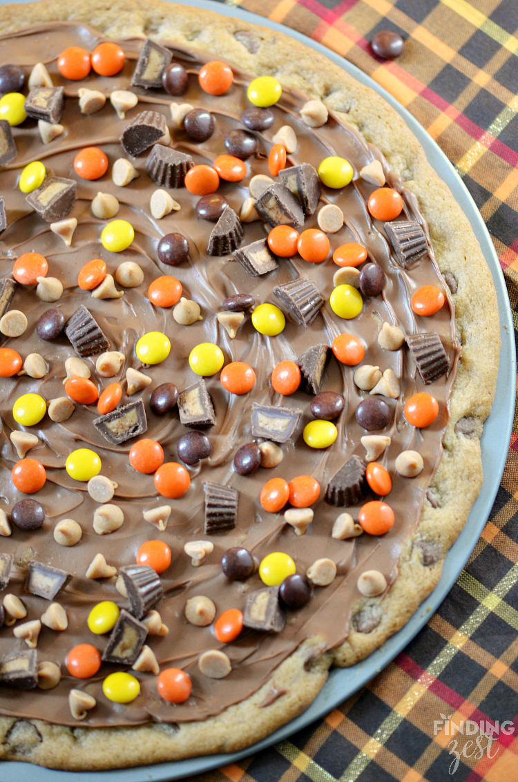 This peanut butter chocolate chip cookie pizza features a chewy chocolate chip cookie base and is covered in peanut butter candies and chocolate! It is sure to impress a crowd!