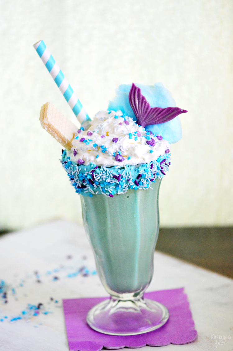 This Mermaid Ice Cream Dream Shake is the perfect dessert for everyday or a mermaid birthday party! Kids will love this fun milkshake featuring a decorated rim, shimmering sprinkles, chocolate mermaid tail and cotton candy wave!