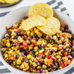 This homemade Black Bean Corn Salsa is sure to be a hit with any crowd! Kick up the flavor to your dinner recipes by serving it as a side dish or as topping to fish, chicken or your favorite Mexican dishes. It also makes for an easy appetizer when served with tortilla chips that everyone will love.