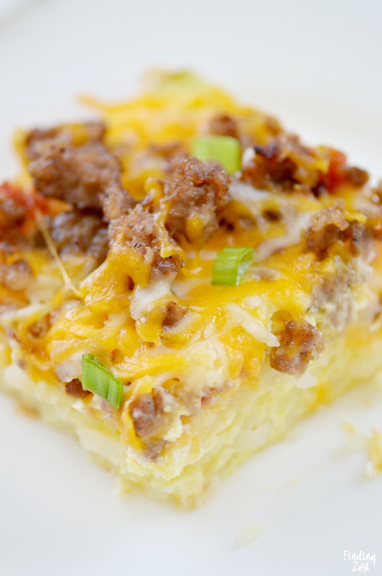 Cut hash brown casserole topped with egg, sausage, cheese and Rotel