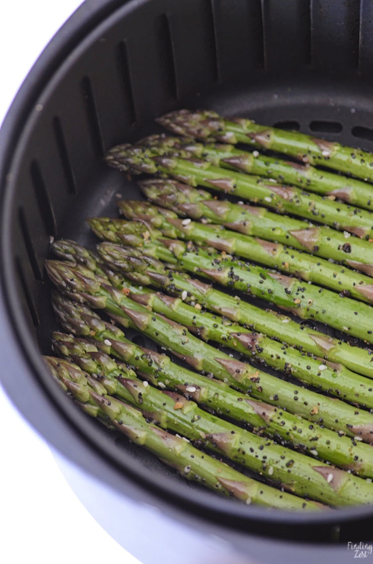Fresh cut asaparagus in a single layer in a basket style air fryer.