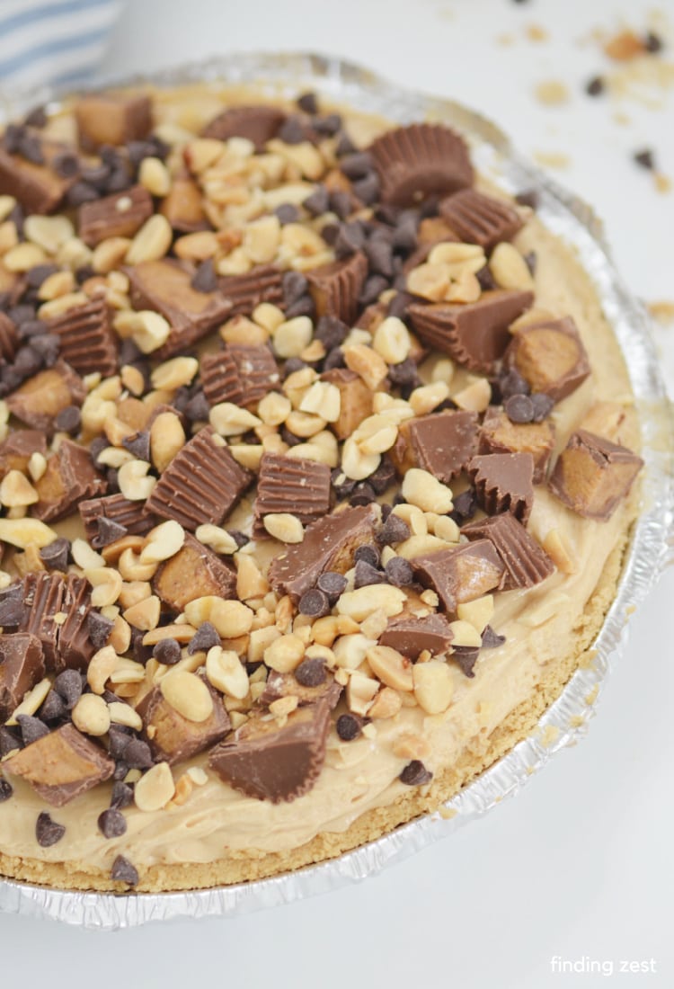 Whole peanut butter pie topped with peanuts, peanut butter cups and mini chocolate chips