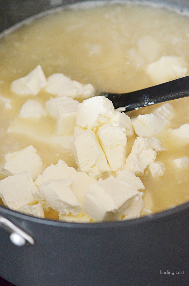 Adding cream cheese into potato soup for an extra creamy broth.
