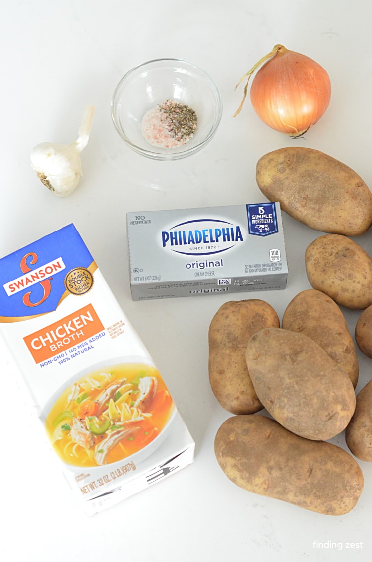 Ingredients needed for a potato soup including chicken broth, potatoes, cream cheese, onion, garlic, salt and pepper