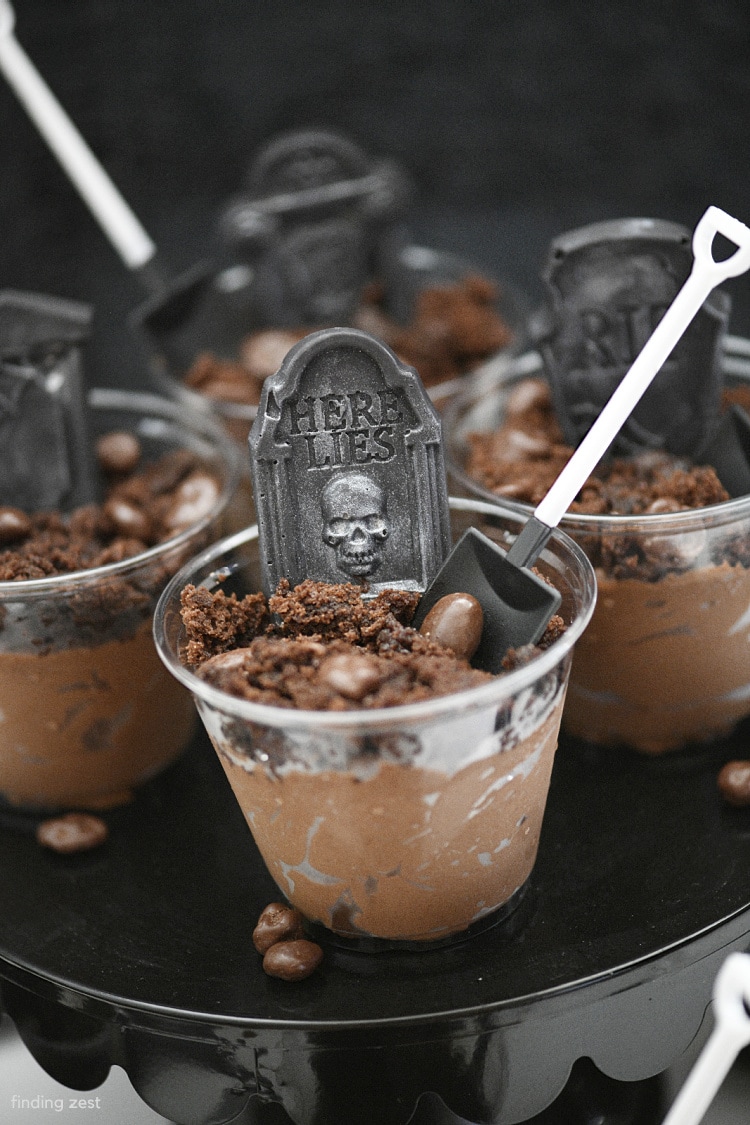 Traditional Halloween Dirt Pudding Graveyard desserts just got a major upgrade with the addition of realistic but edible gravestones! You won't believe just how easy they are to make. Features an amazing chocolate mousse made with pudding and topped with brownie and a shovel spoon!