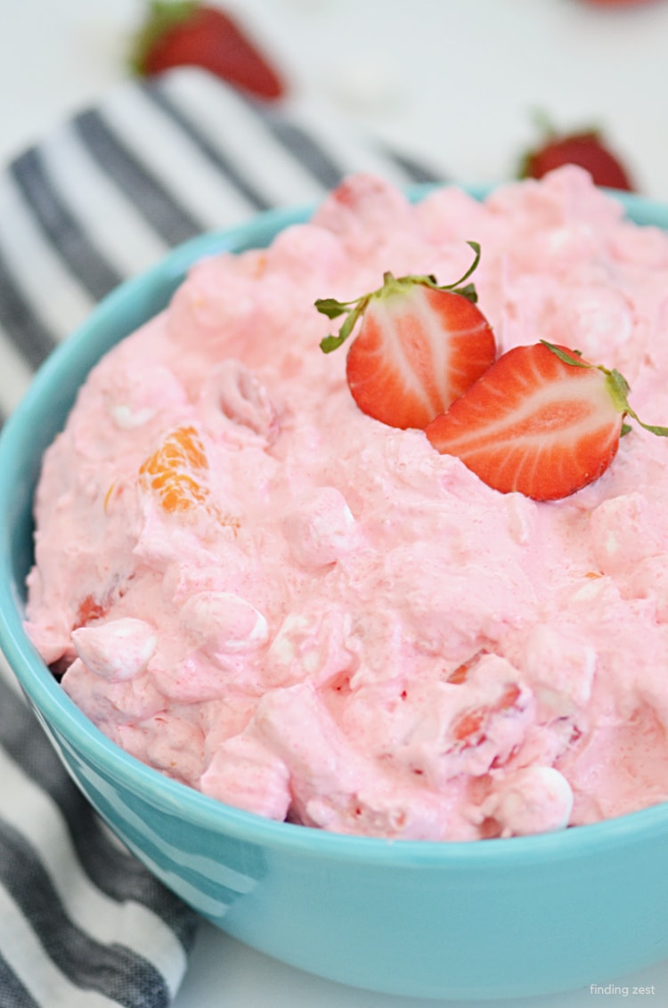Strawberry Fluff Salad features fresh strawberries, canned fruit, mini marshmallows, cool whip and Jello! No pudding required in this refreshing fruit salad that is perfect for holiday celebrations or your next potluck gathering.