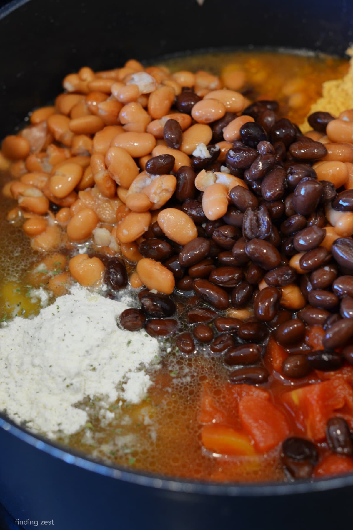 Taco soup cooking on the stove with beans, beef, corn, chicken broth, Rotel, diced tomatoes, ranch dressing and taco seasoning. 