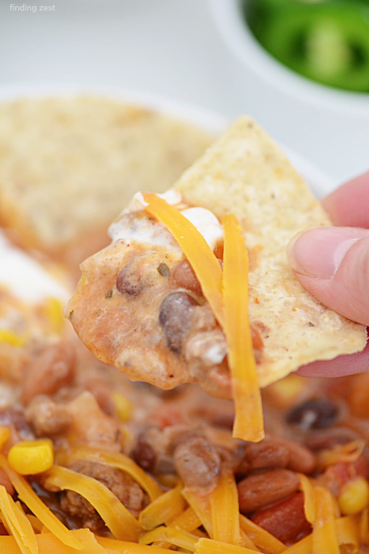 A hearty taco soup with tortilla chips, sour cream and shredded cheese. 