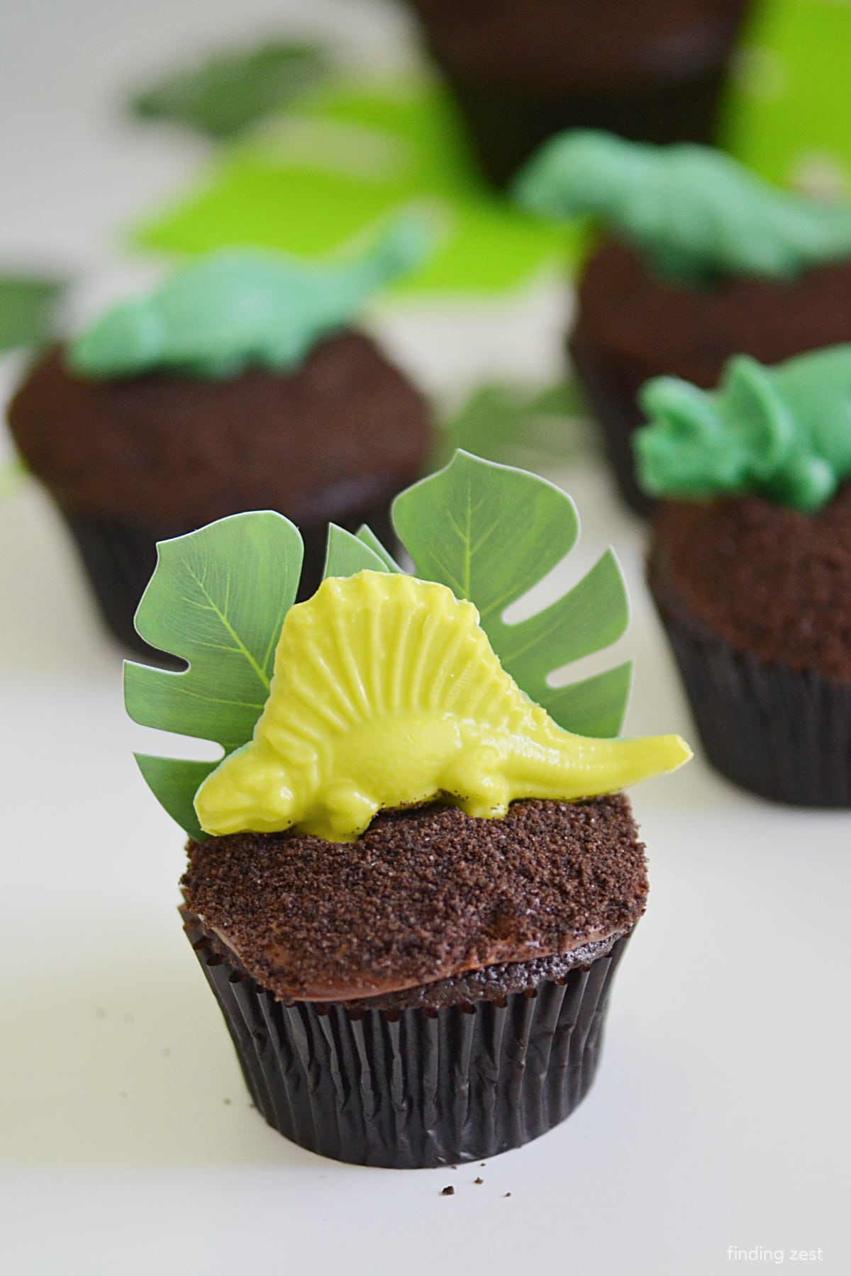 These dinosaur cupcakes are perfect for a birthday party. They're easy to make and use a box mix, so they're fast too! Easy to frost and top with crushed Oreos for dirt, they are topped off with chocolate dinosaurs for the perfect finish. Step-by-step instructions included!