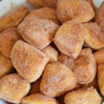 These donut holes are easy to make and taste delicious. Perfect for an everyday snack or a special holiday treat. Simply quarter some canned biscuits, bake them in your air fryer, brush them with butter and then toss them in cinnamon in sugar. So simple but they taste amazing!