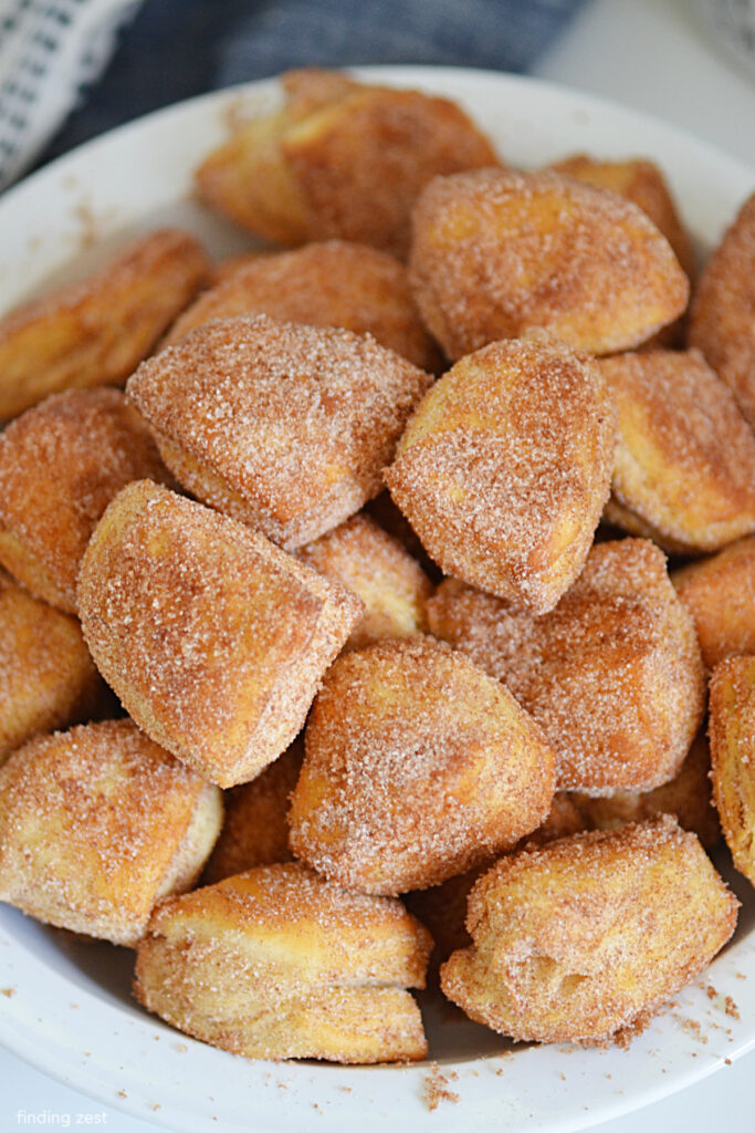 These donut holes are easy to make and taste delicious. Perfect for an everyday snack or a special holiday treat. Simply quarter some canned biscuits, bake them in your air fryer, brush them with butter and then toss them in cinnamon in sugar. So simple but they taste amazing!