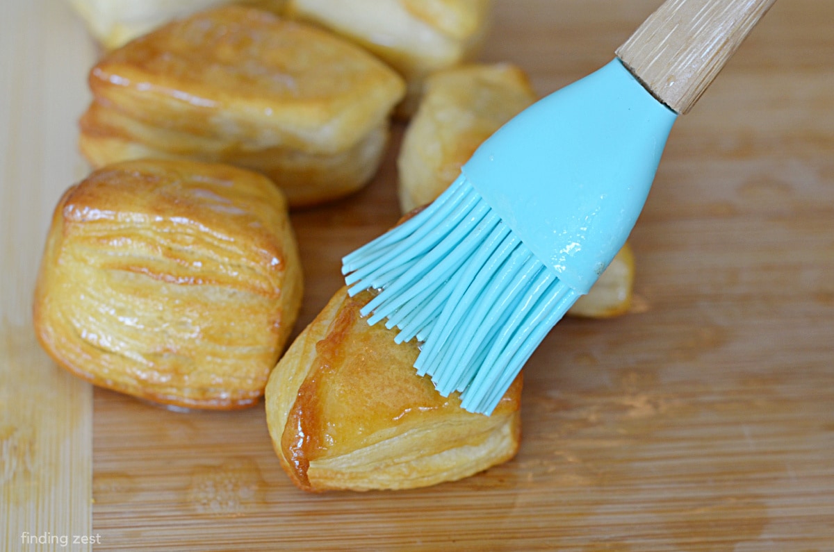 Badigeonner de beurre sur les trous de beignets pour la cannelle et le sucre