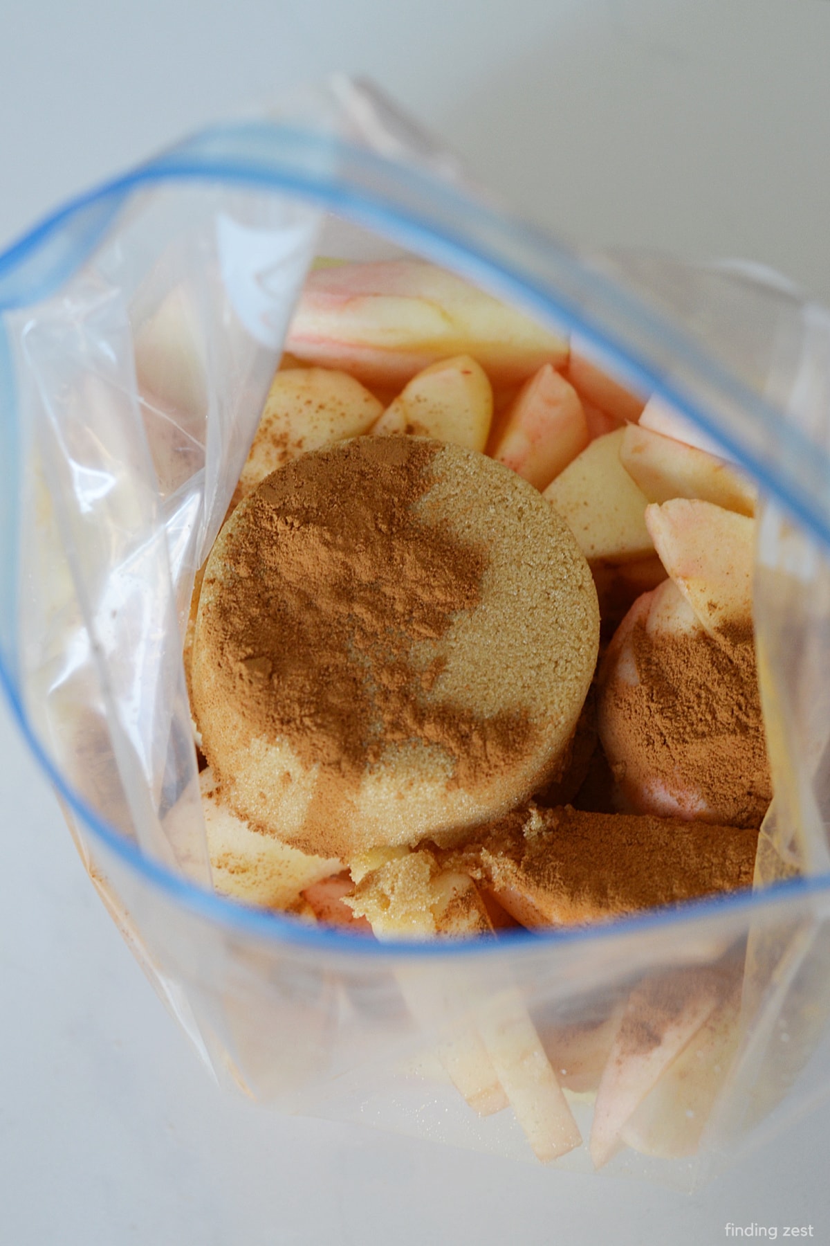 Adding brown sugar and cinnamon to sliced apples in a bag.