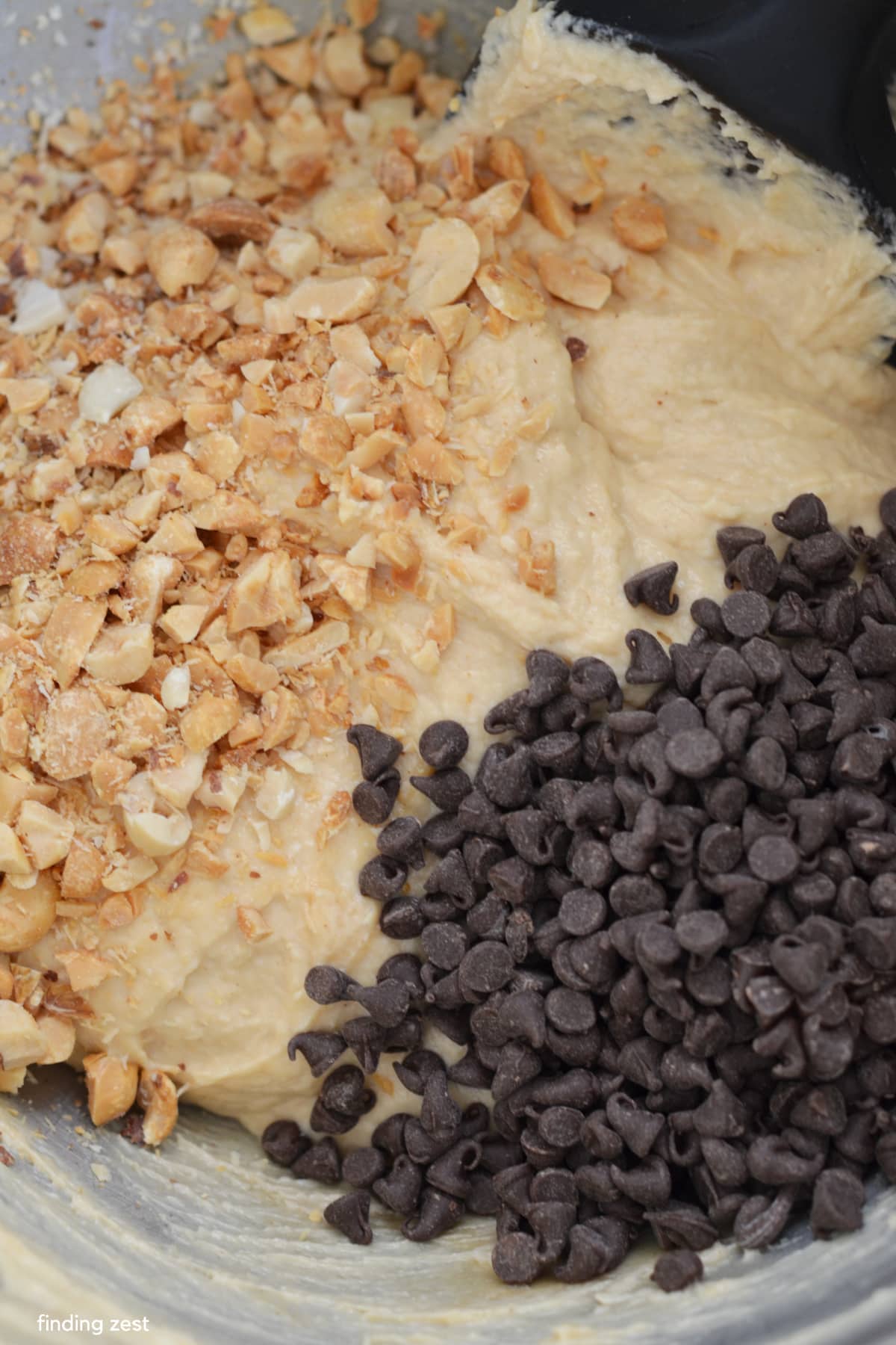 Adding chopped peanuts and mini chocolate chips to peanut butter dip with cream cheese