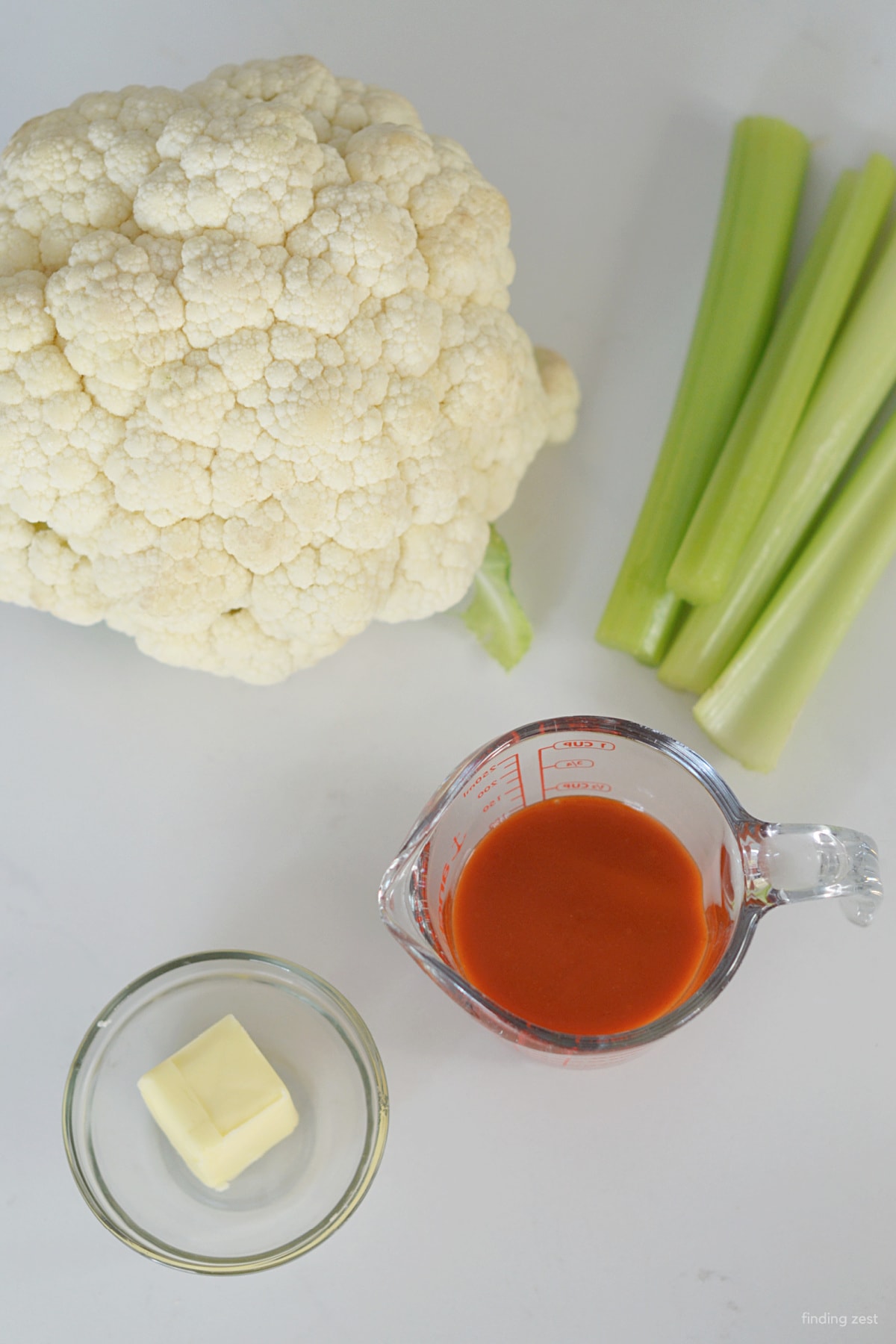 Ingredients to make buffalo cauliflower recipe including buffalo sauce and butter