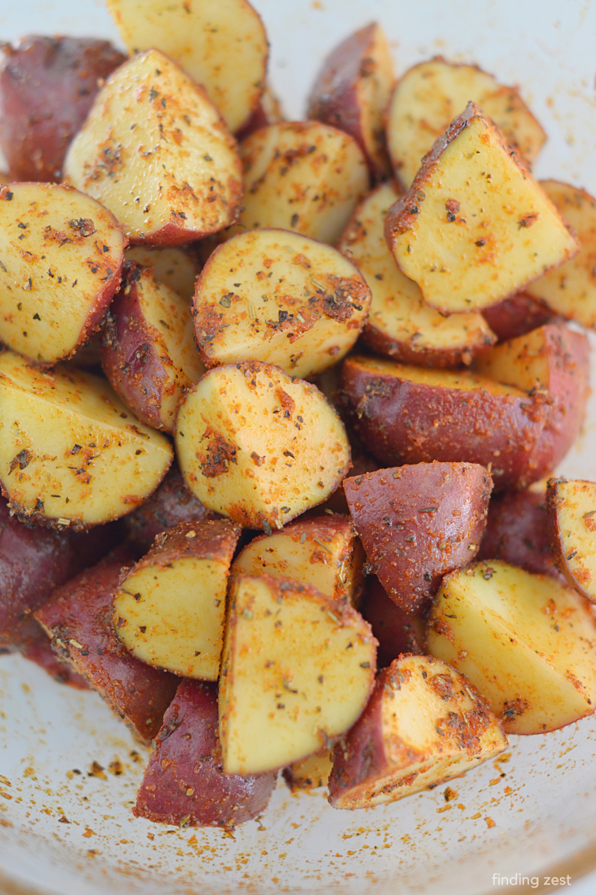 Adding simple seasonings and spices to baby red potatoes cut into wedges.