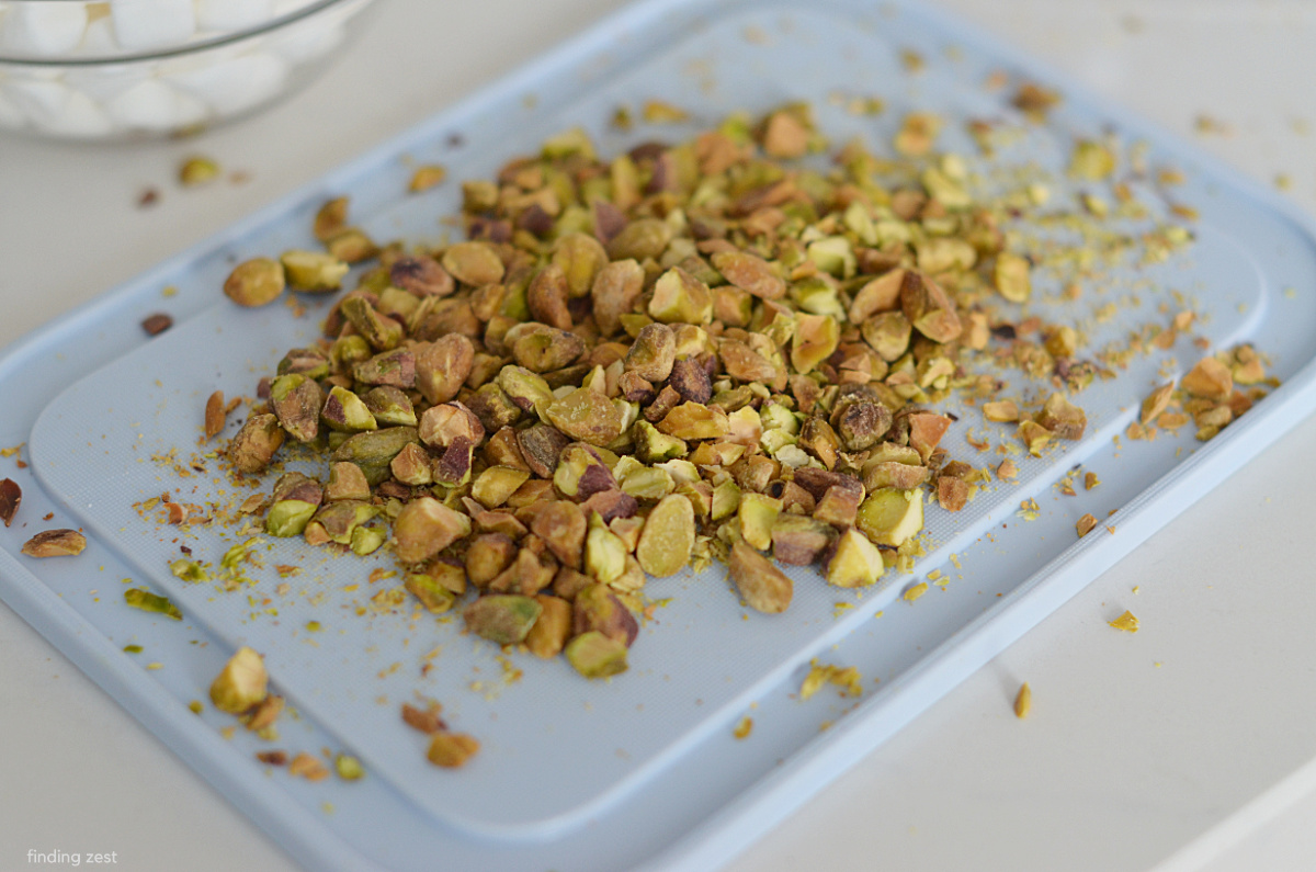 Chopped pistachios on a cutting board for a fruit salad