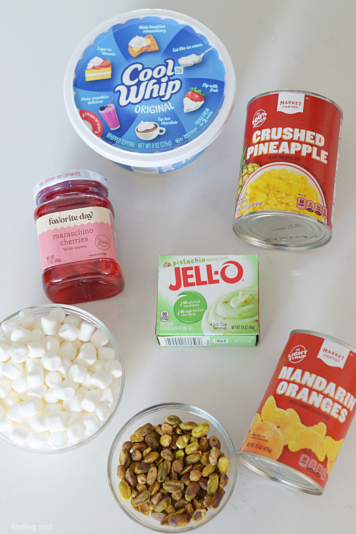 Ingredients needed for Pistachio Fluff including pistachio pudding, crushed pineapple, mandarin oranges, mini marshmallows, pistachios and cool whip!