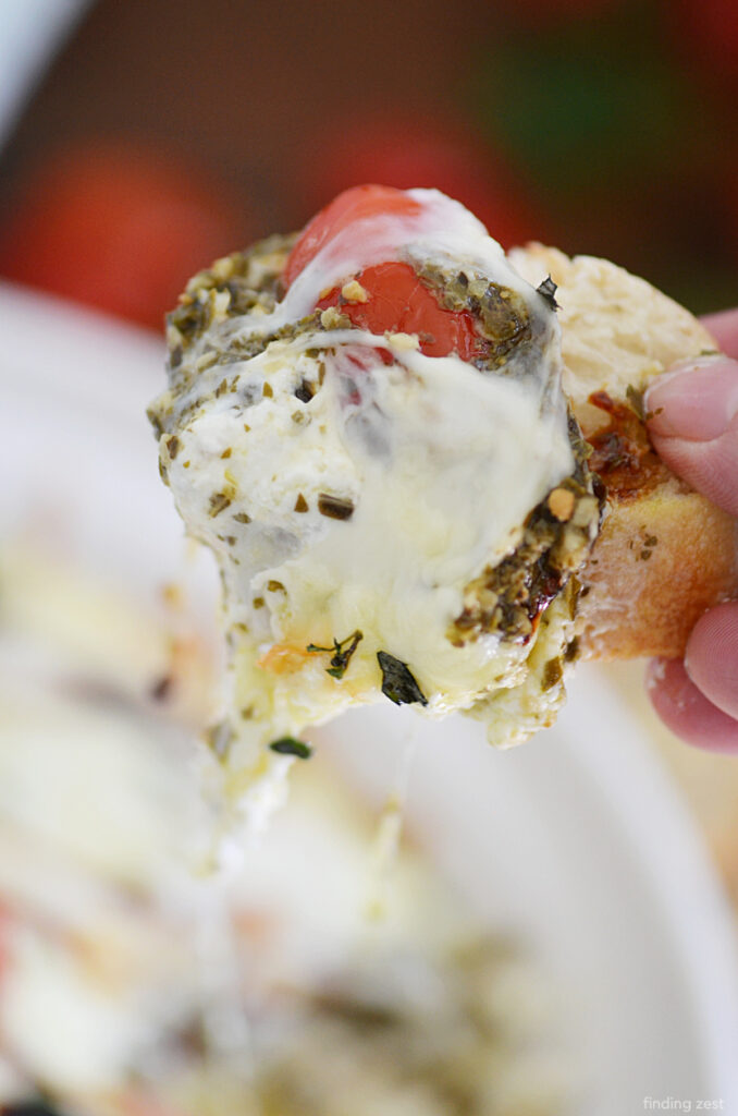 This caprese dip is so delicious and cheesy! Loaded with flavor, this easy party food features cream cheese, cherry tomatoes, pesto and plenty of melty mozzarella cheese!