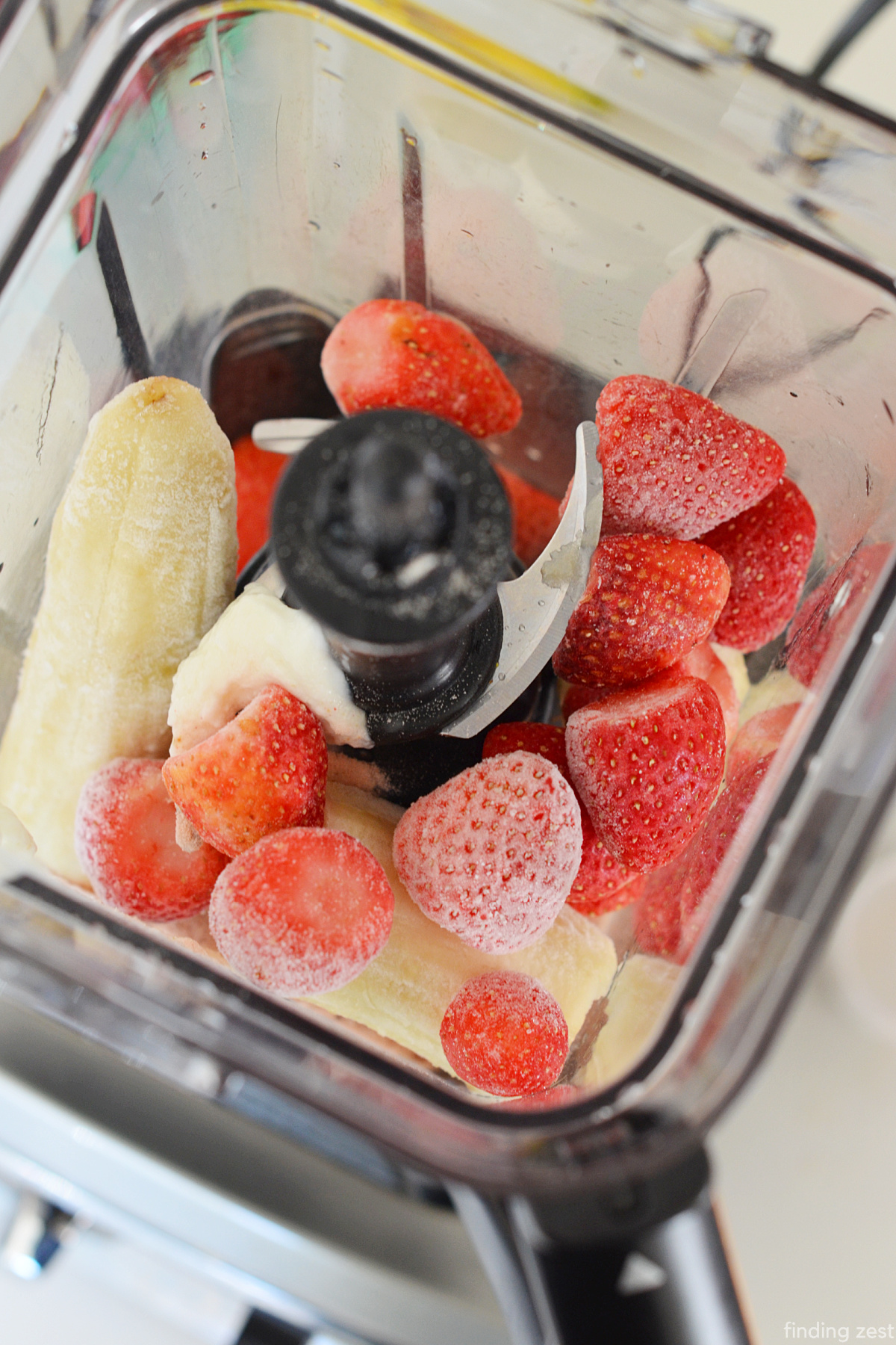 Frozen strawberries, banana, yogurt and protein powder in a blender